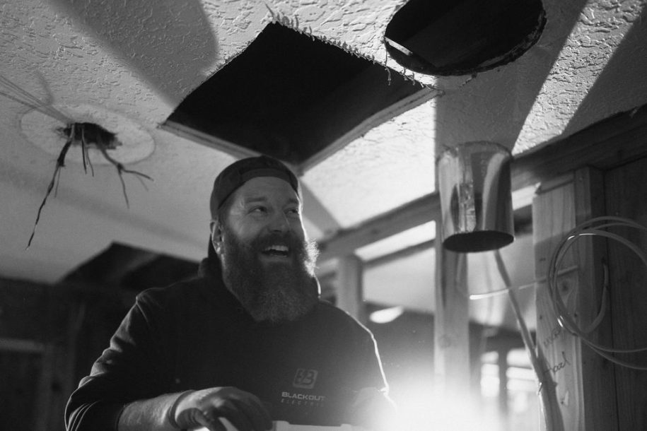 Blackout Electric electrician working beneath a ceiling light opening