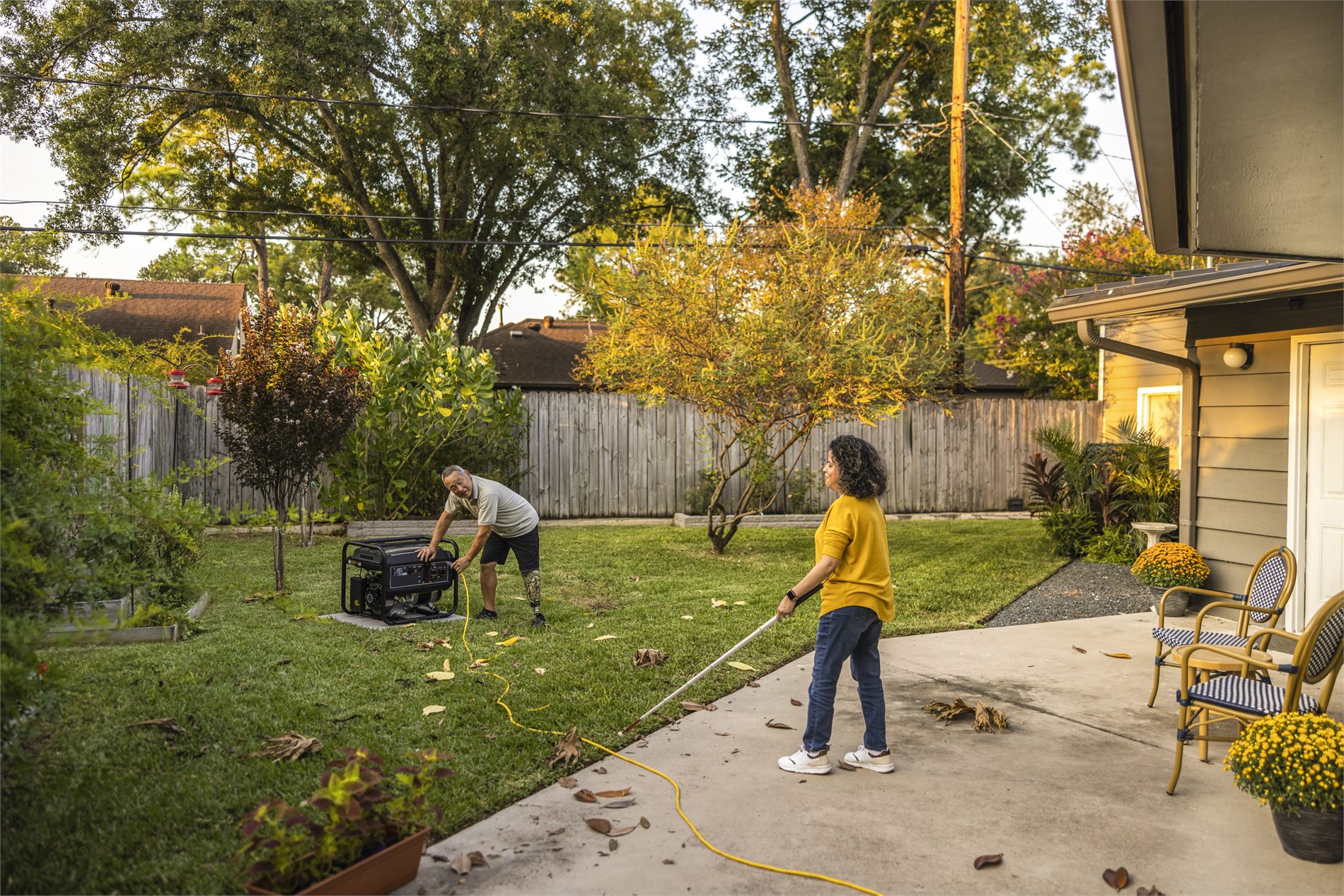 Homeowners positioning a portable backup generator outdoors beside a house
