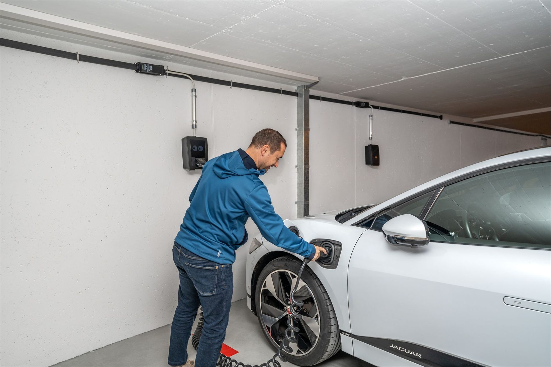 Driver connecting an electric vehicle to a garage charging station