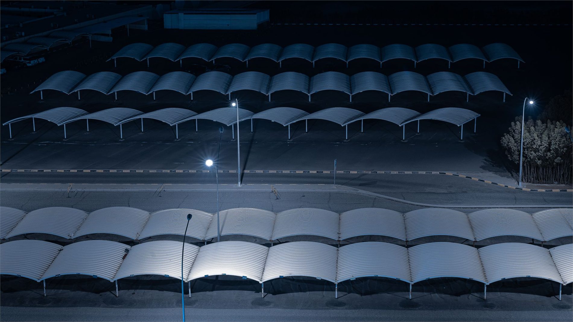 Bright pole lights illuminating a covered commercial parking lot at night