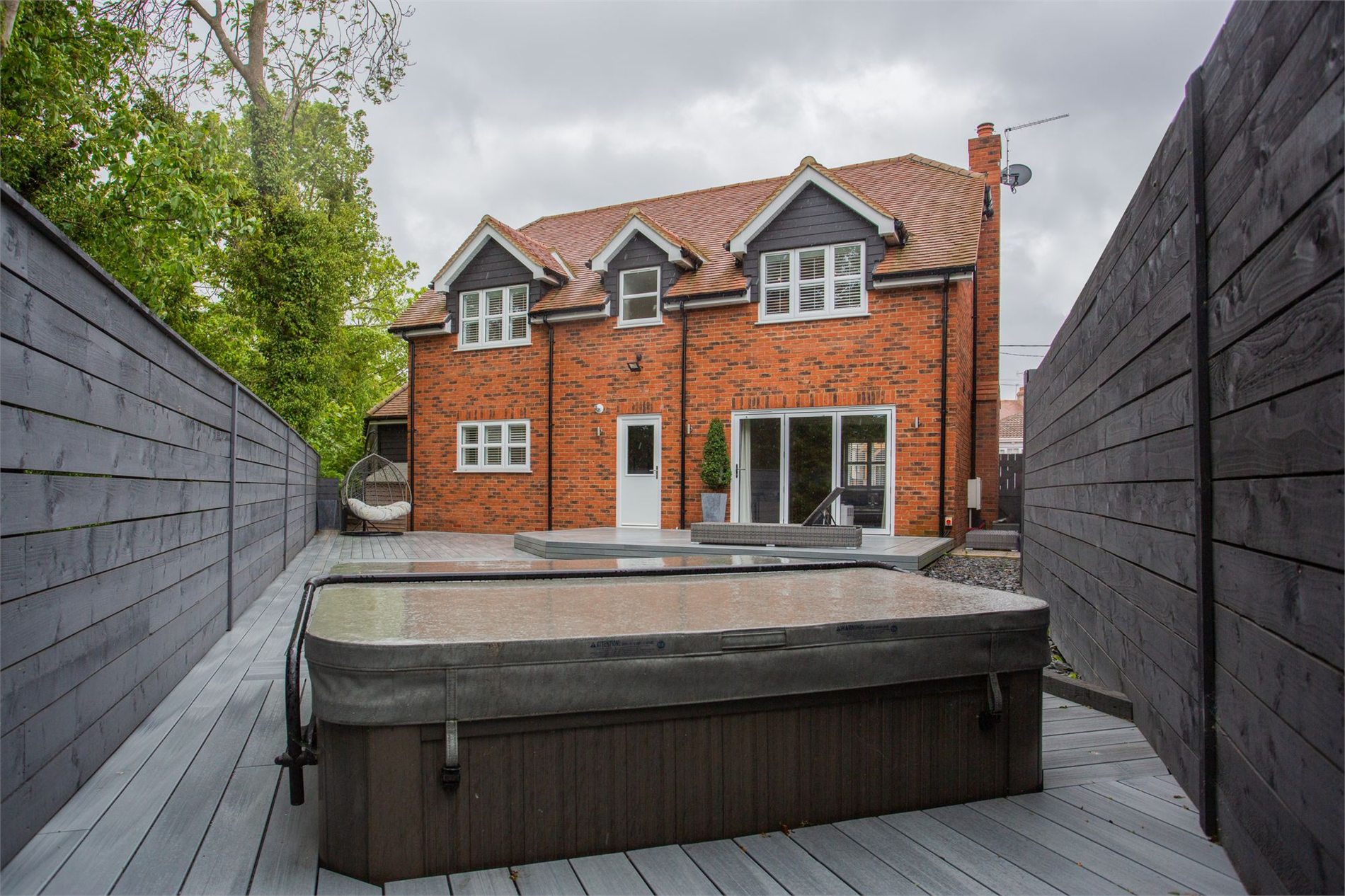 Covered hot tub positioned on a deck behind a residential home