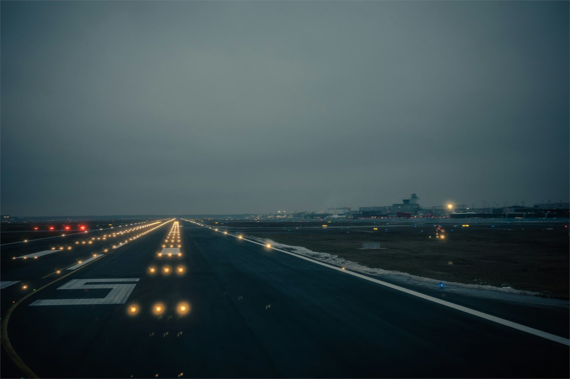 Airport runway and taxiway lighting guiding the pavement at dusk