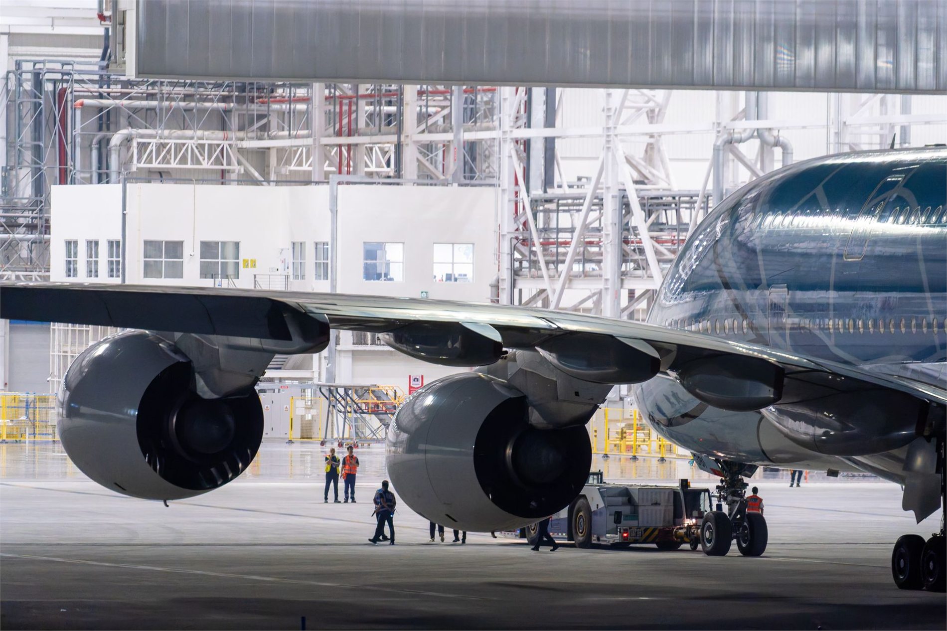 Commercial airplane undergoing maintenance inside a brightly lit hangar