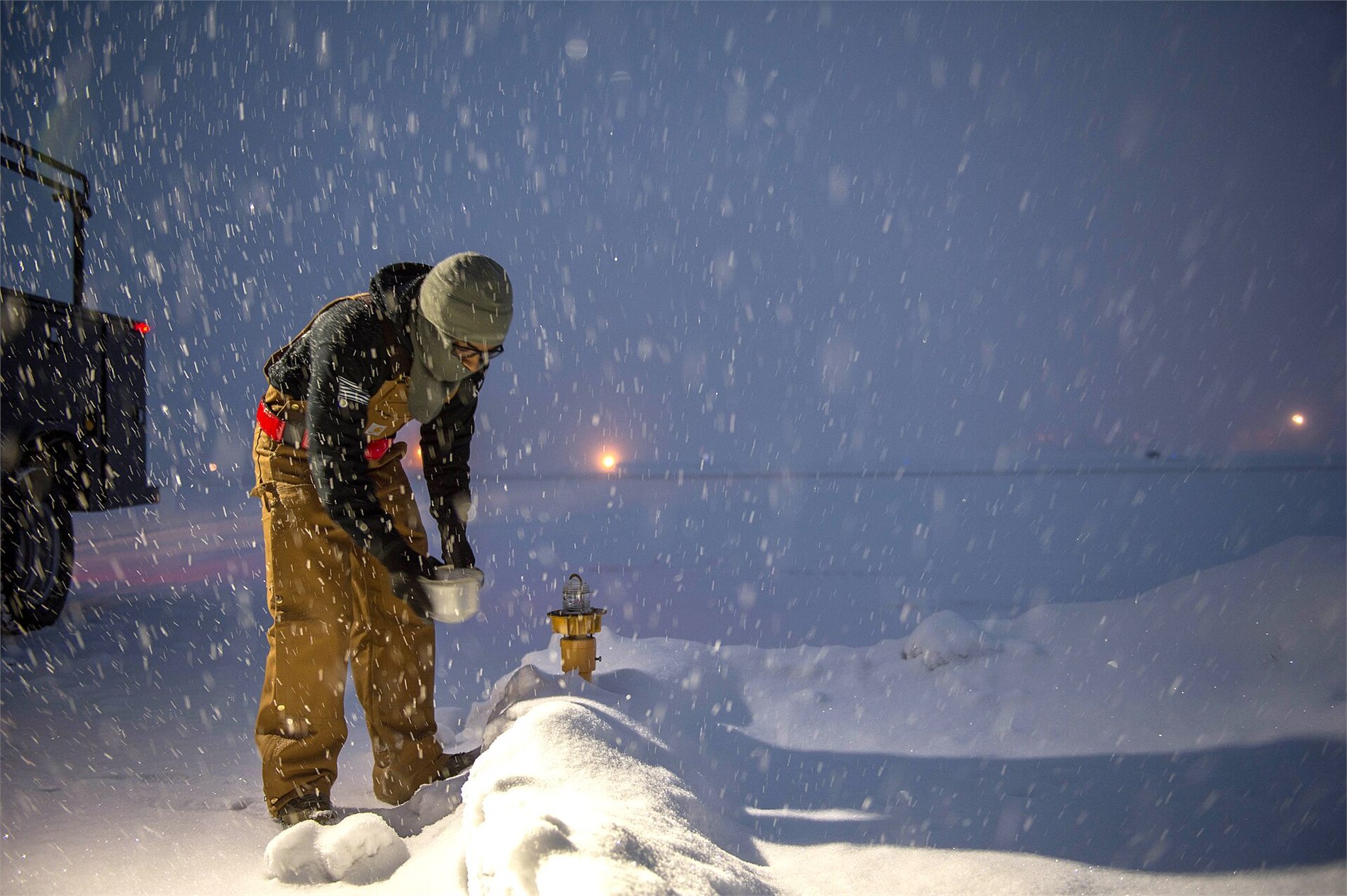 Electrical systems technician servicing an airport runway light in winter conditions