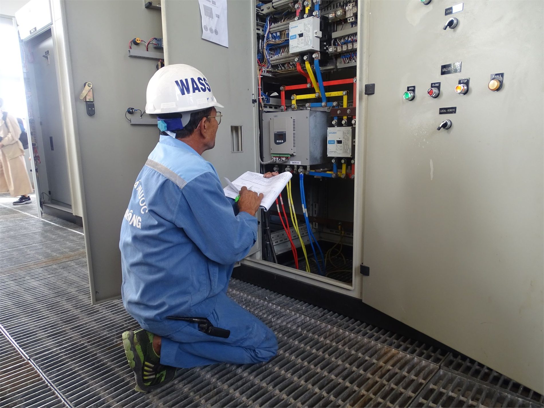 Engineer inspecting wiring inside an industrial electrical panel