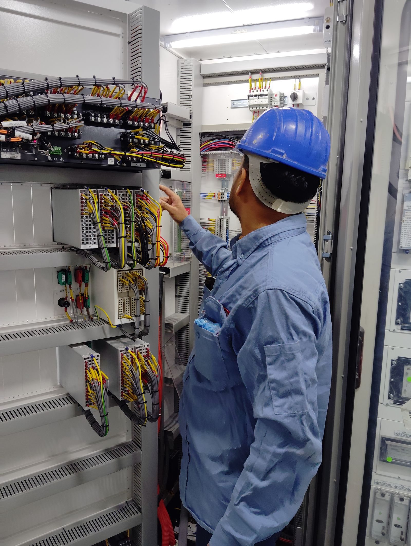 Industrial electrician inspecting organized wiring inside an electrical control cabinet