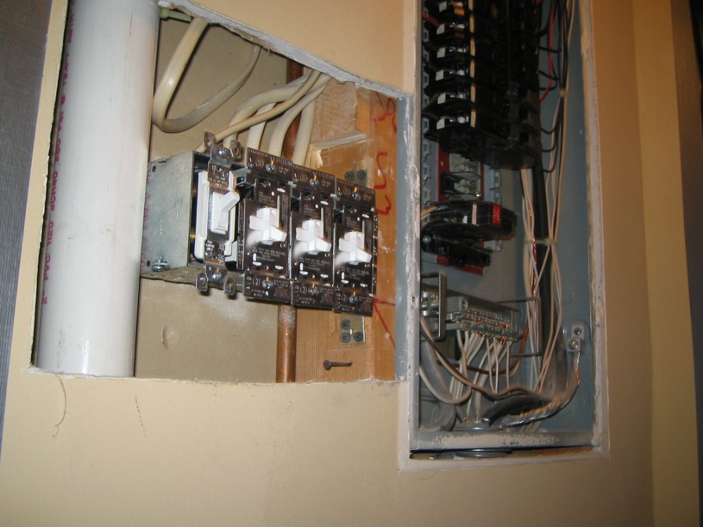 Older U.S. breaker panel and exposed wiring during renovation