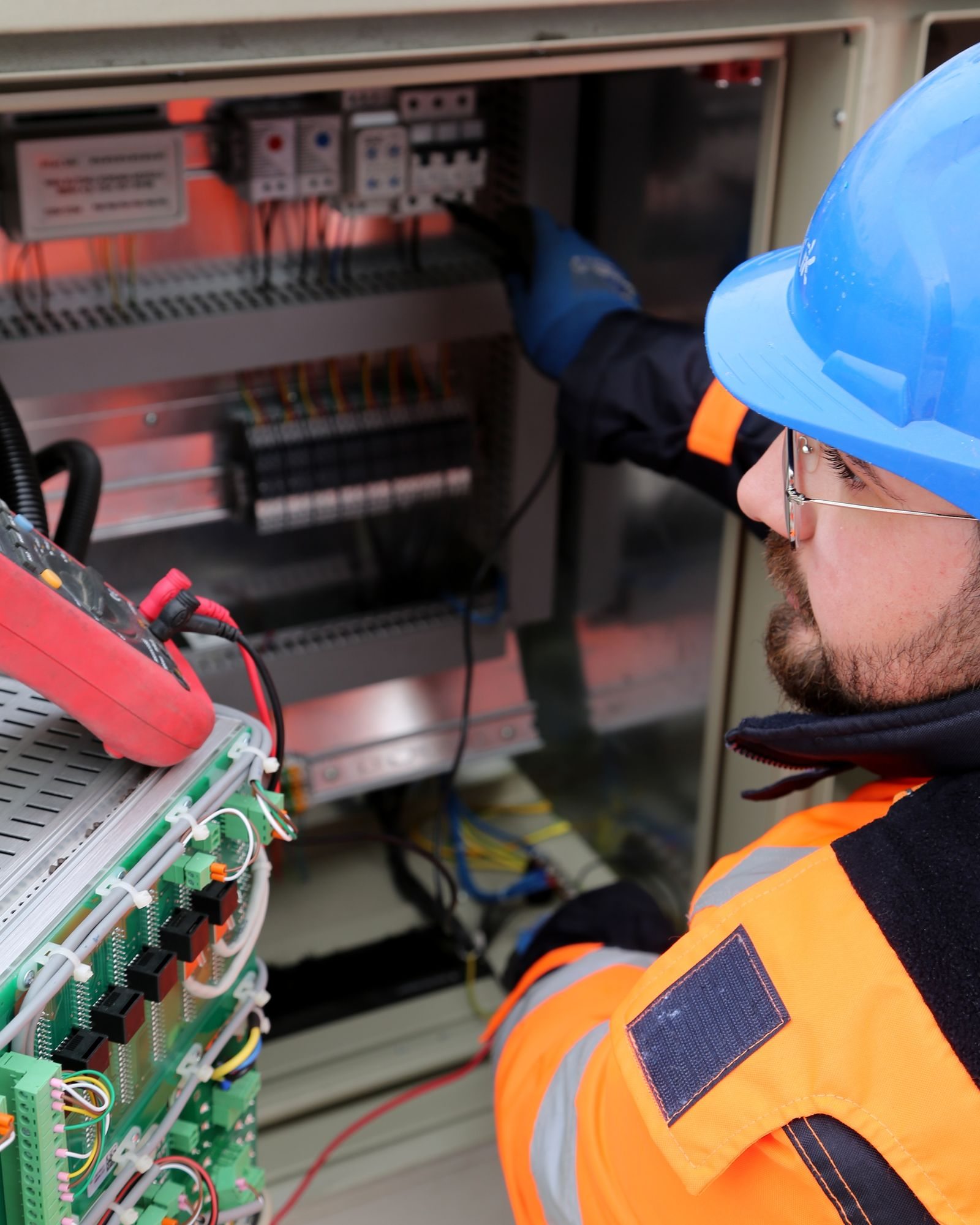 Electrician testing equipment inside a facility electrical distribution cabinet