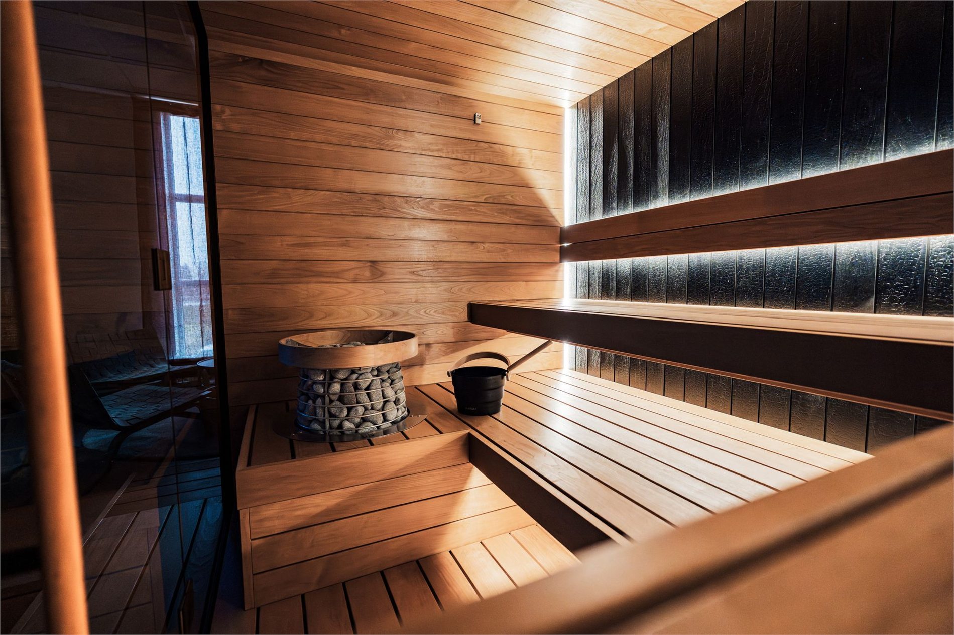 Modern home sauna with an electric stone heater and warm wood benches