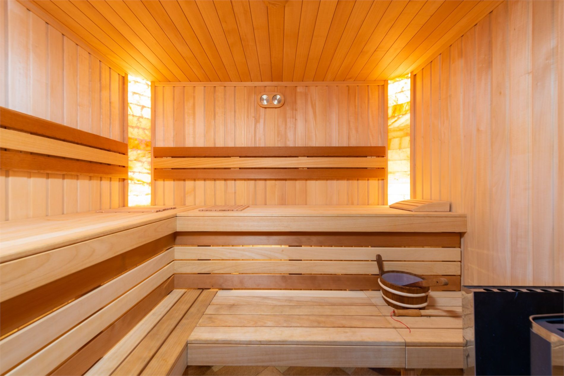Finished residential sauna with tiered wood benches and heater area