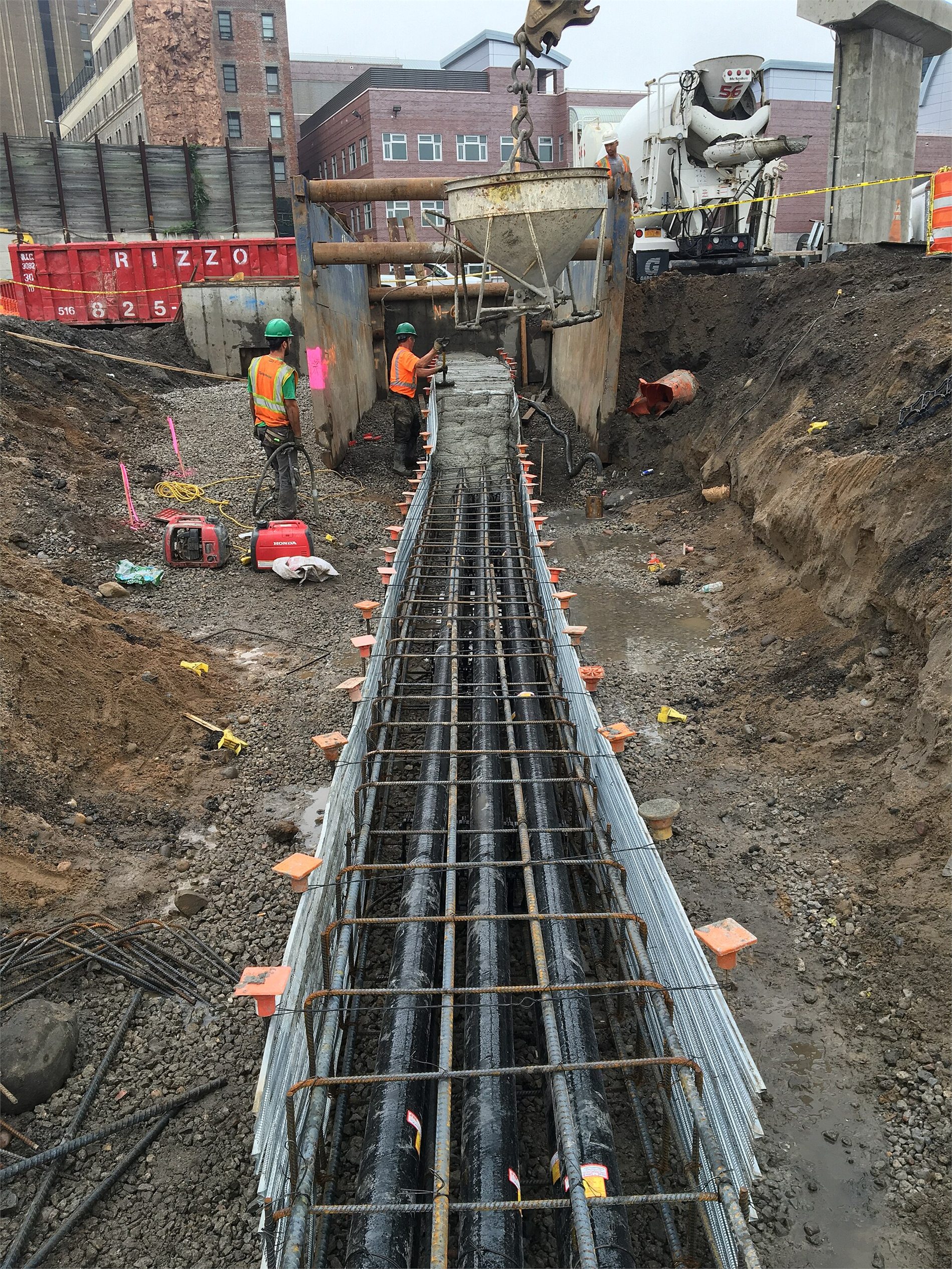 Electrical duct bank conduits being installed in an excavated utility trench
