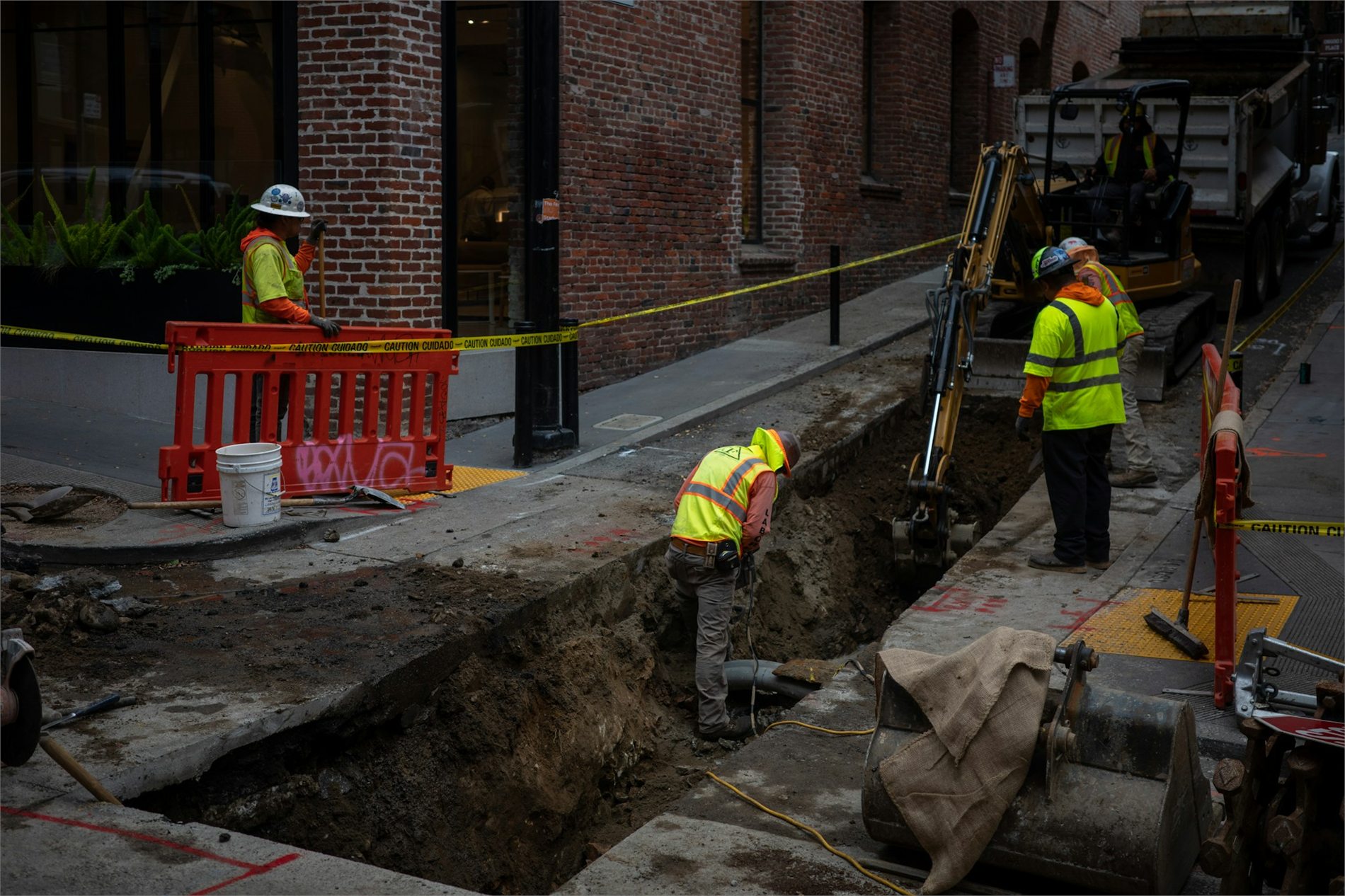 Construction crew excavating a utility trench along a city street